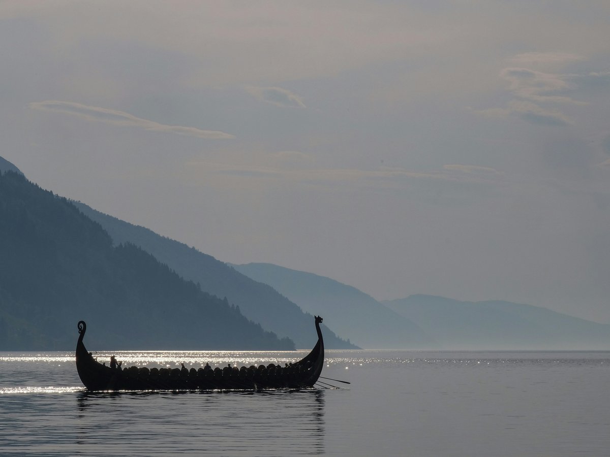 a long boat with two people in it on a lake