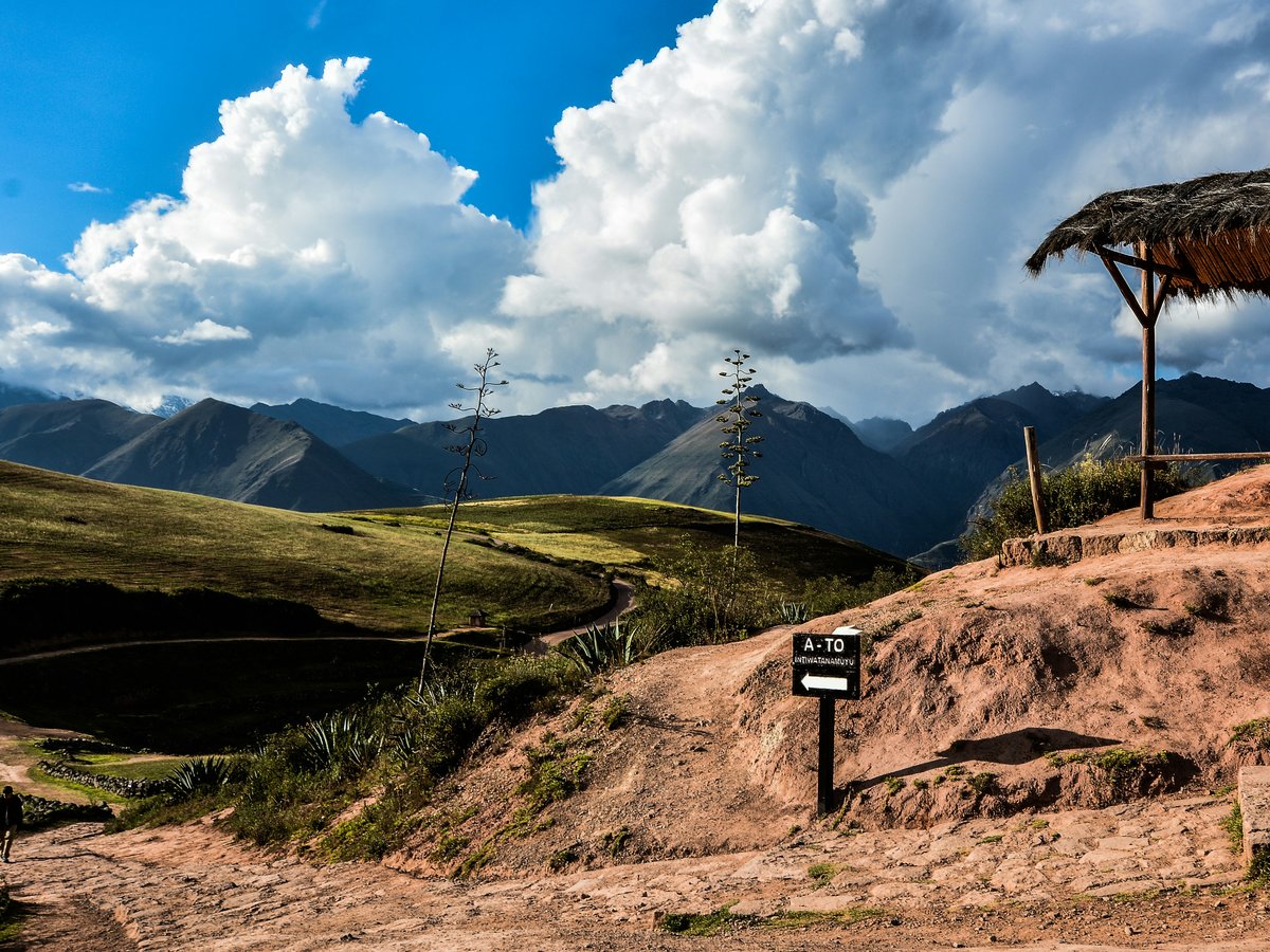 green grass field and mountain under blue sky and white clouds during daytime