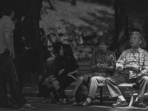 grayscale photo of man and woman sitting on bench