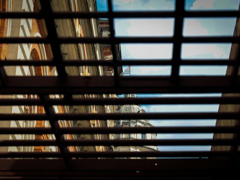 Architectural buildings and sky visible through a dark grate.