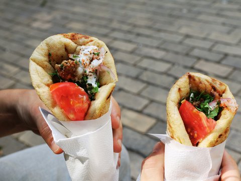 A person holding two sandwiches in their hands