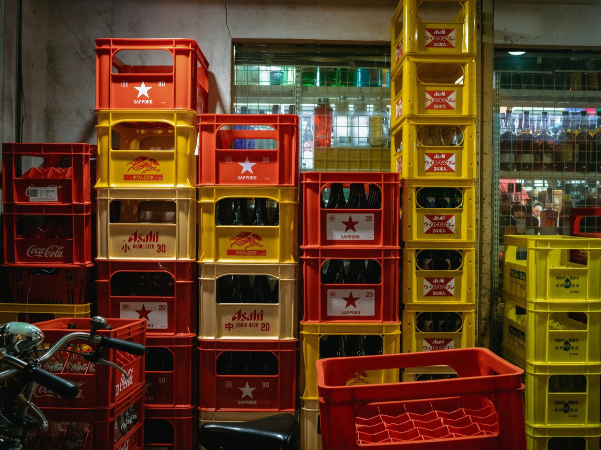Stacks of red and yellow crates filled with bottles.