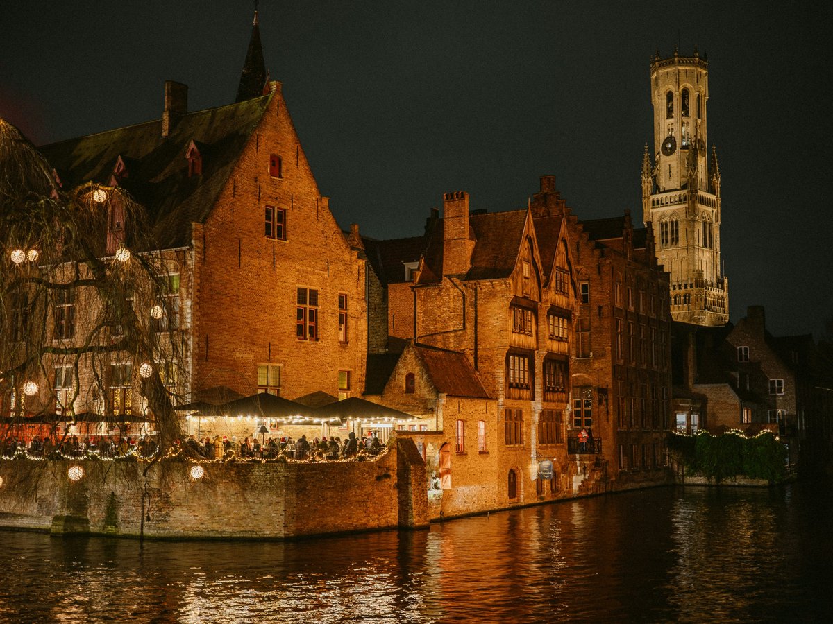 Historic buildings illuminated at night along a canal.