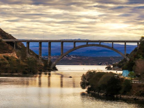 gray concrete bridge over river under gray clouds