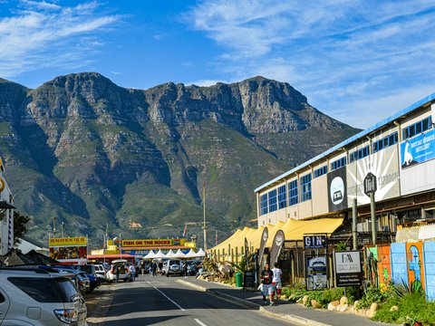 A street with cars parked on both sides and mountains in the background