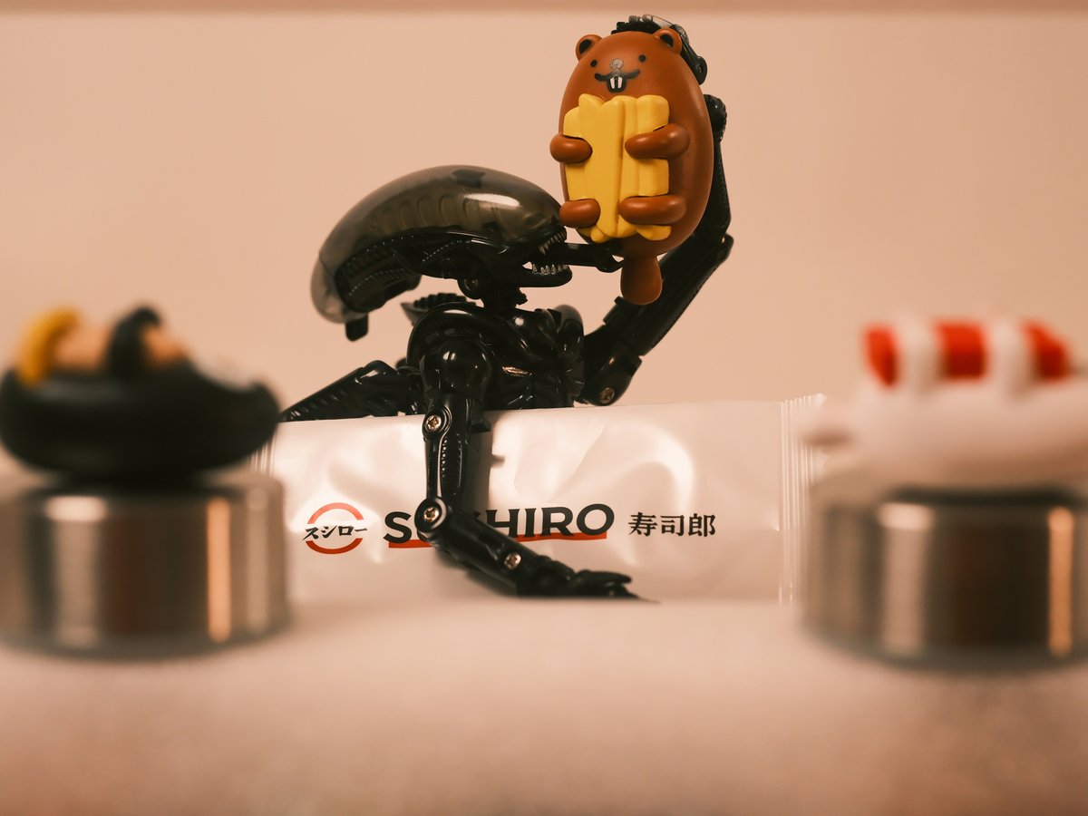 Alien figurine holding a hot dog with small figurines