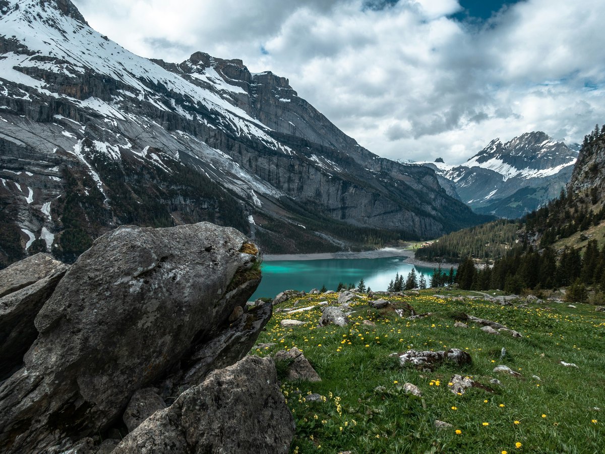 A view of Oeschinensee lake surrounded by snow-capped mountains in Kandersteg, Switzerland