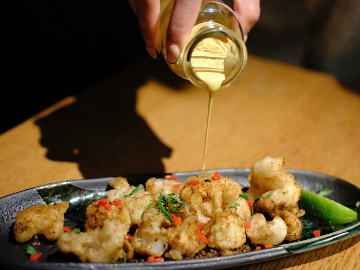 a person pouring sauce on a plate of food