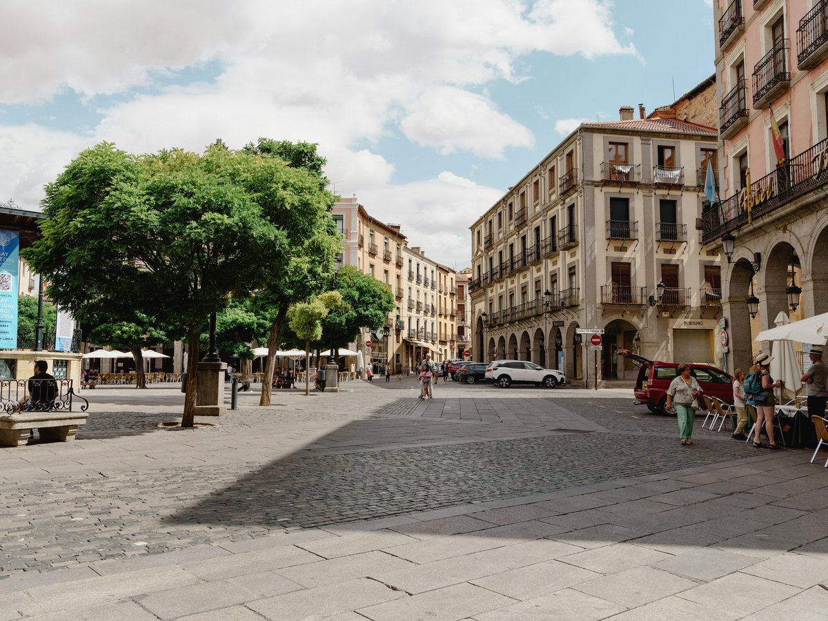 a city square with tables and umbrellas on a sunny day