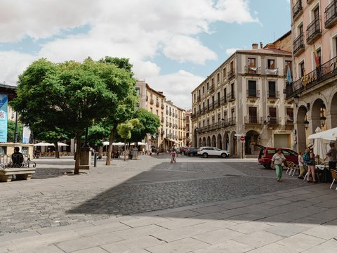 a city square with tables and umbrellas on a sunny day