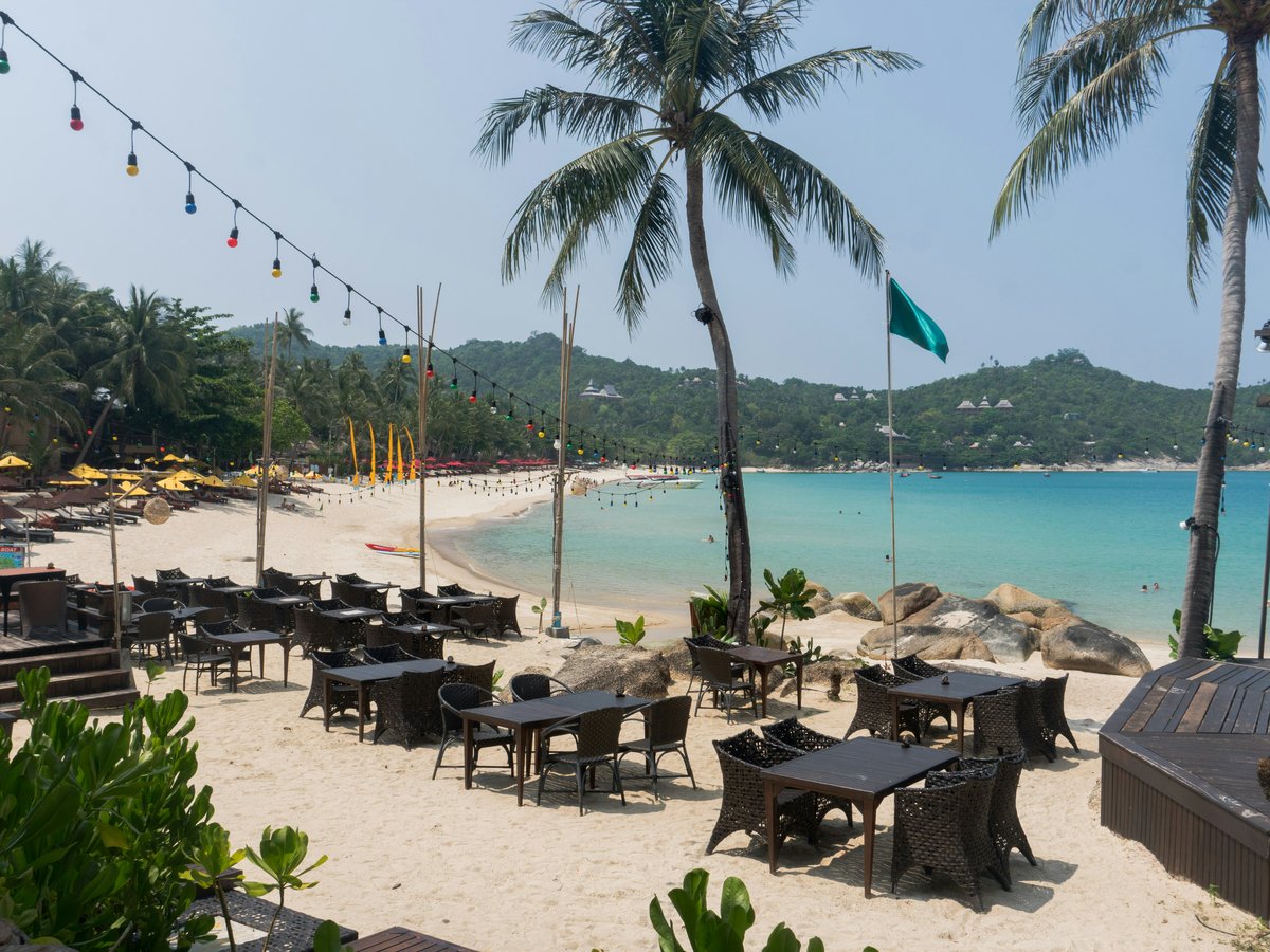 A sandy beach with tables and umbrellas on it