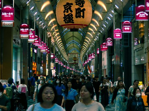 a group of people walking down a street next to tall buildings