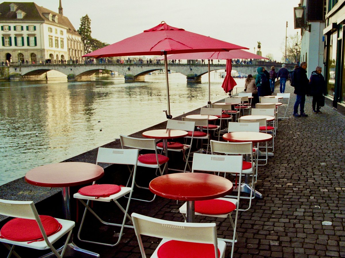 Outdoor cafe with red tables and chairs by a river