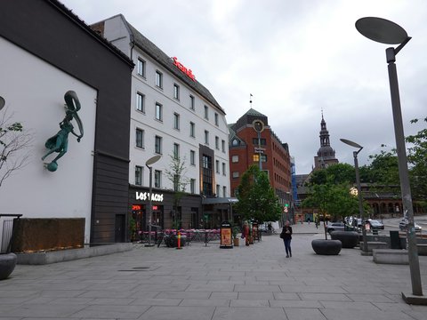 City square with modern buildings and a distant church spire.