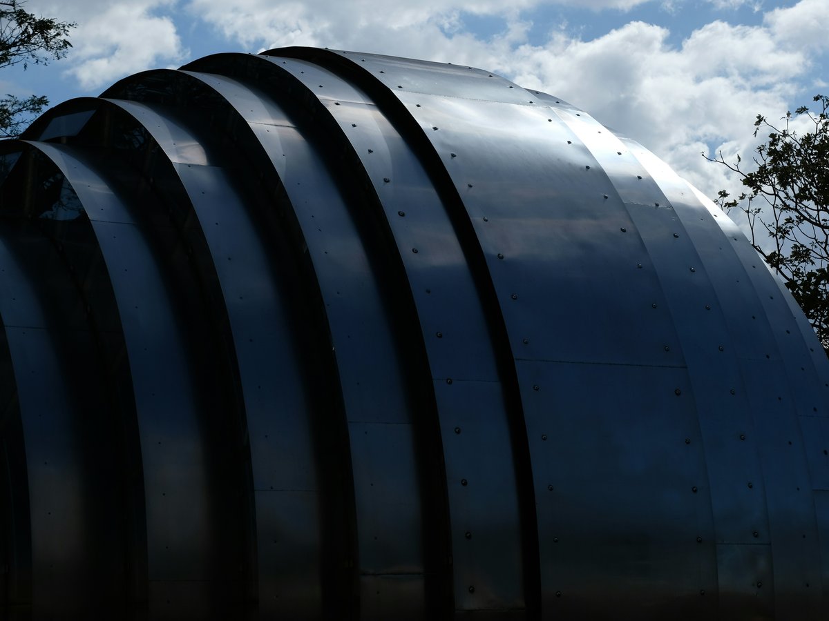 a large metal structure sitting next to a forest