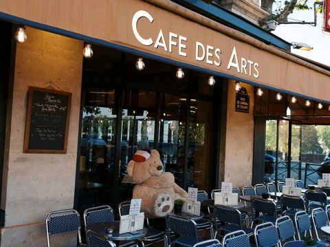 A teddy bear sitting in the window of a cafe