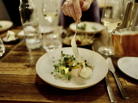 A person holding a spoon over a plate of food