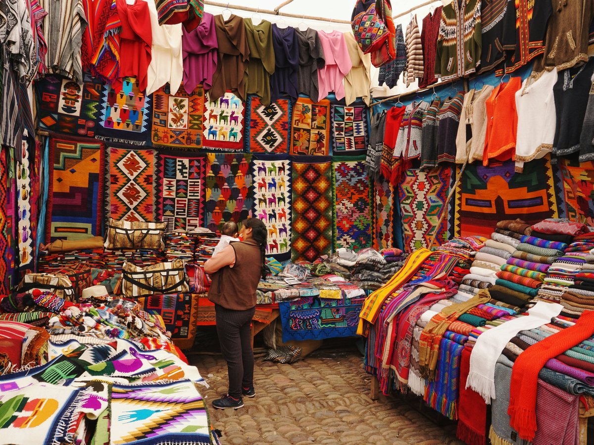 woman in store with display of assorted shirts and textiles