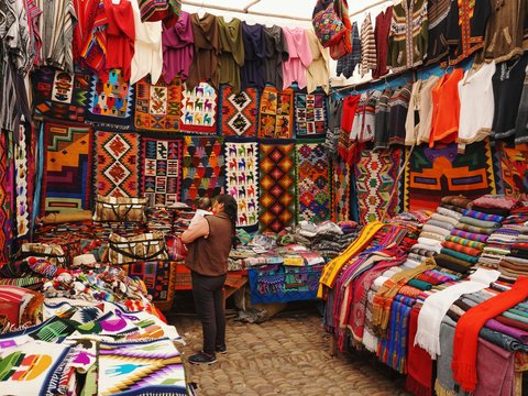 woman in store with display of assorted shirts and textiles