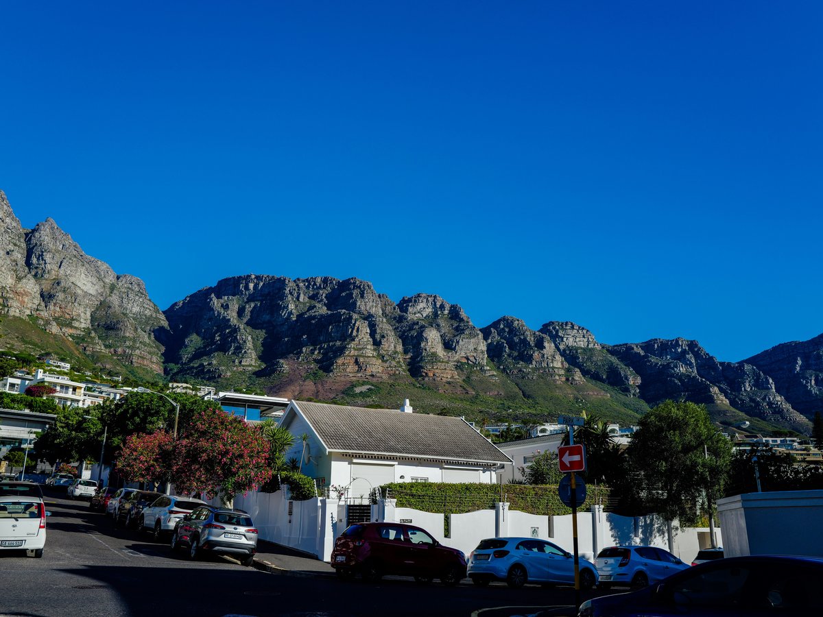 Mountain range overlooking a suburban street with parked cars.