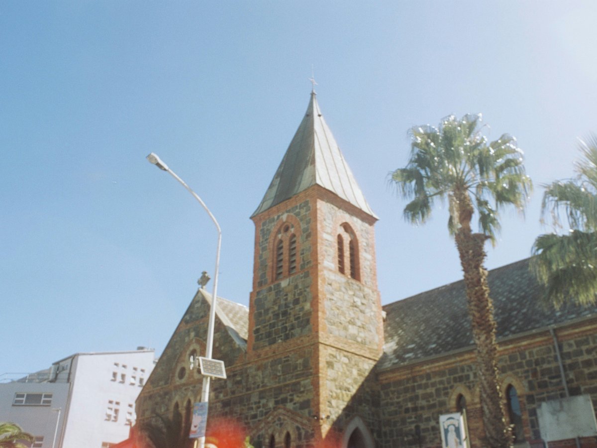 a church with a tall steeple surrounded by palm trees