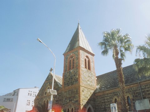 a church with a tall steeple surrounded by palm trees