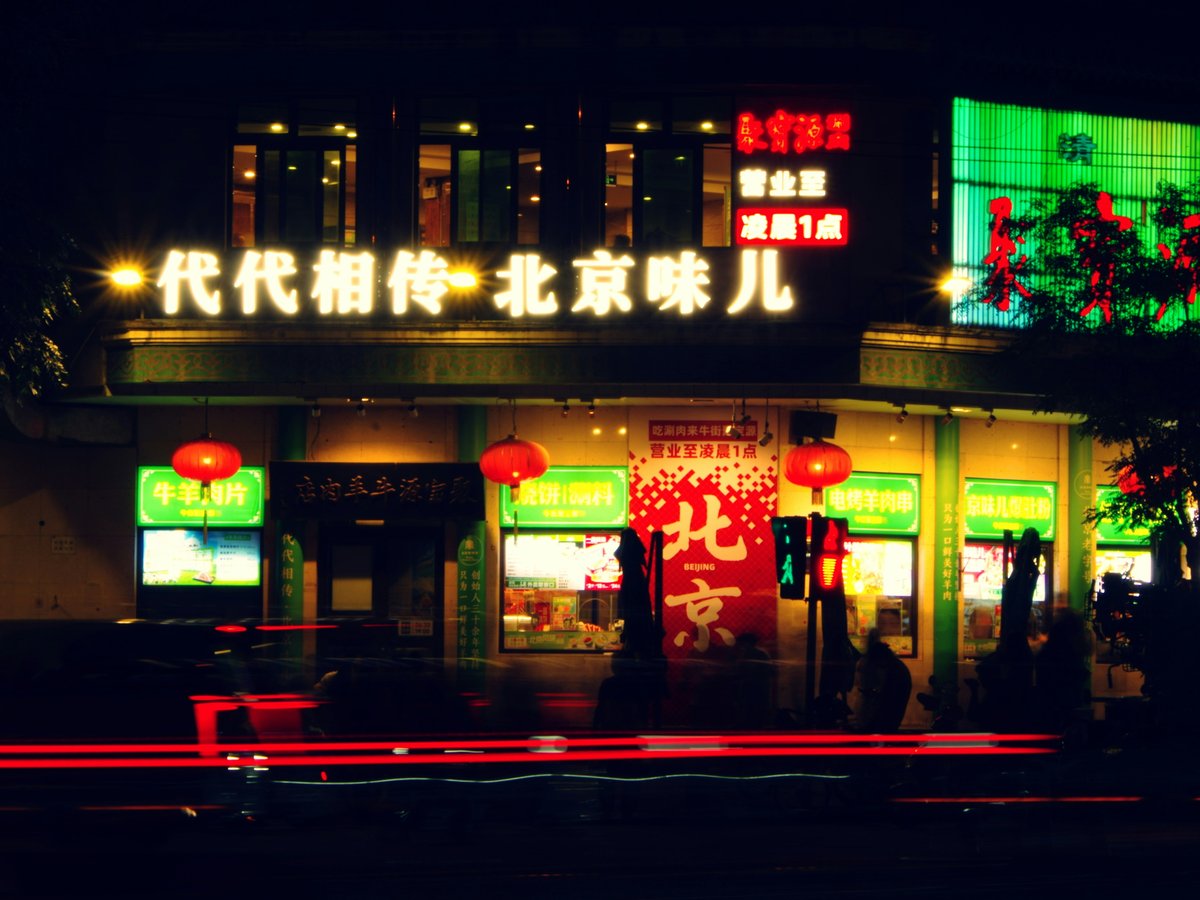 A brightly lit restaurant at night with light trails