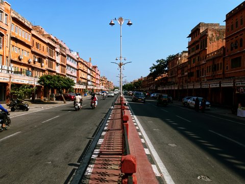 A busy street lined with orange buildings and vehicles.