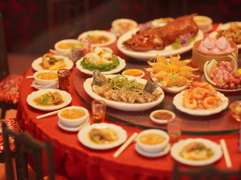 Table laden with diverse asian dishes and roasted pig