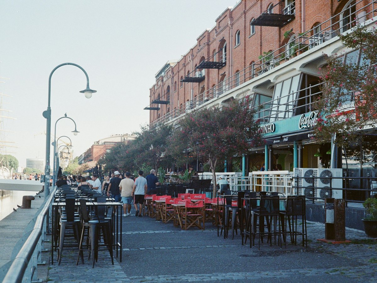 a group of people walking down a street next to tall buildings