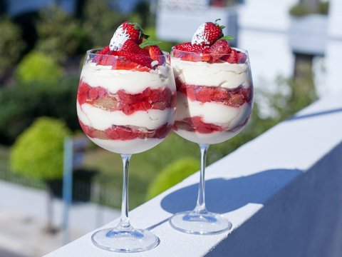 two glasses filled with dessert sitting on a ledge