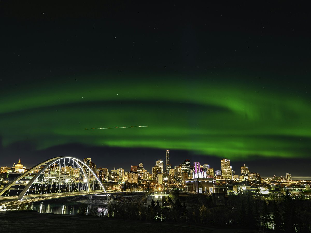 a green aurora bore over a city at night