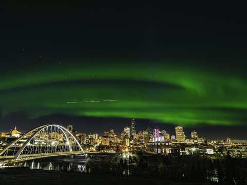 a green aurora bore over a city at night