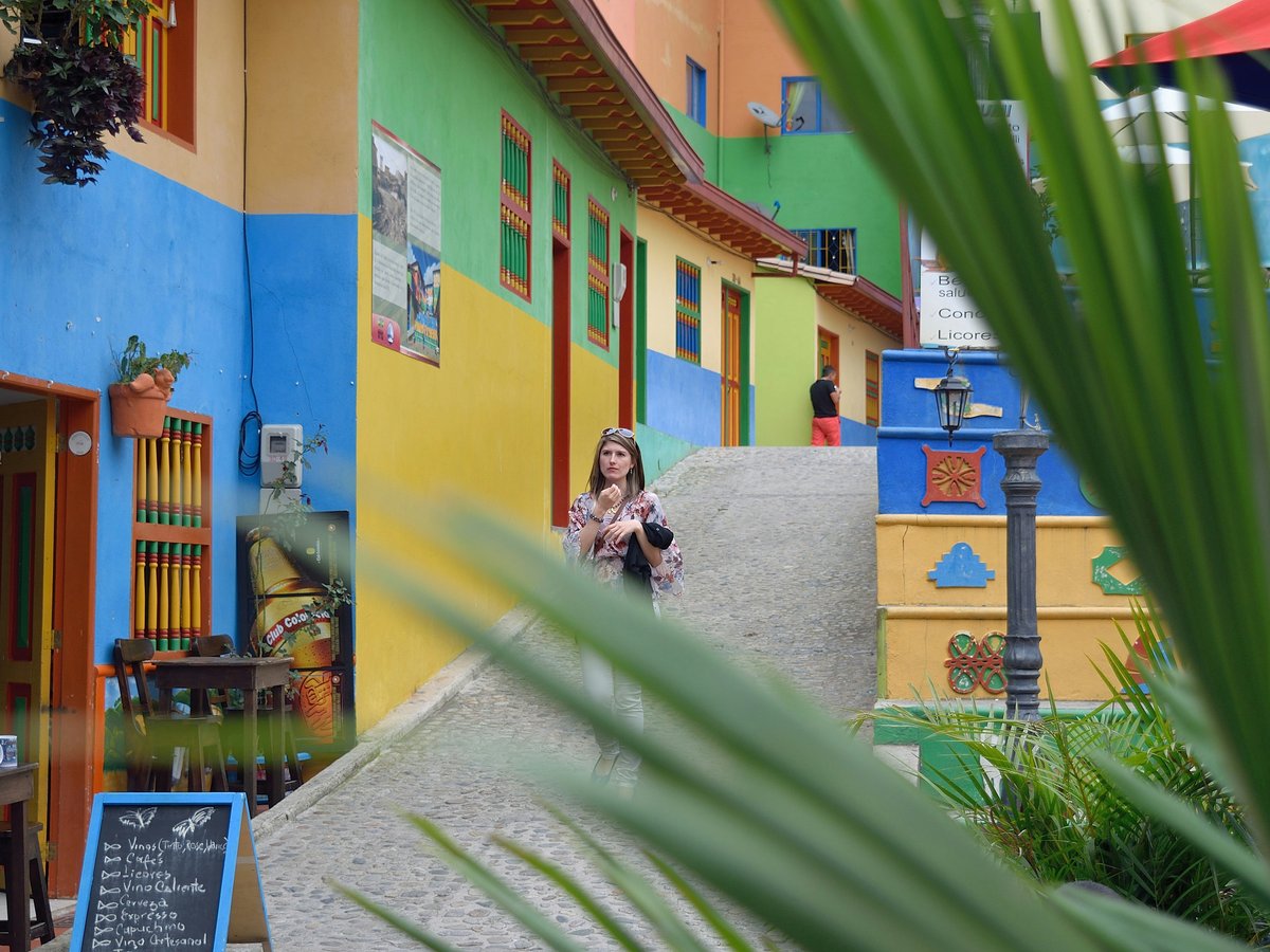 A person walks down a colorful street with vibrant buildings.