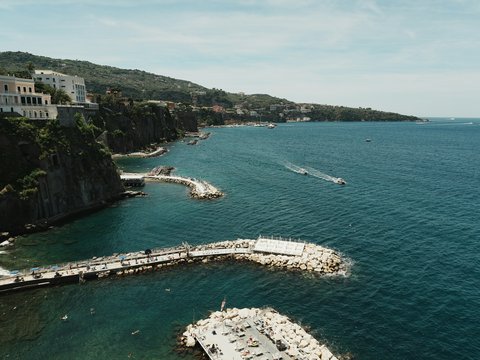 Beautiful coastline with piers, cliffs, and boat on blue sea