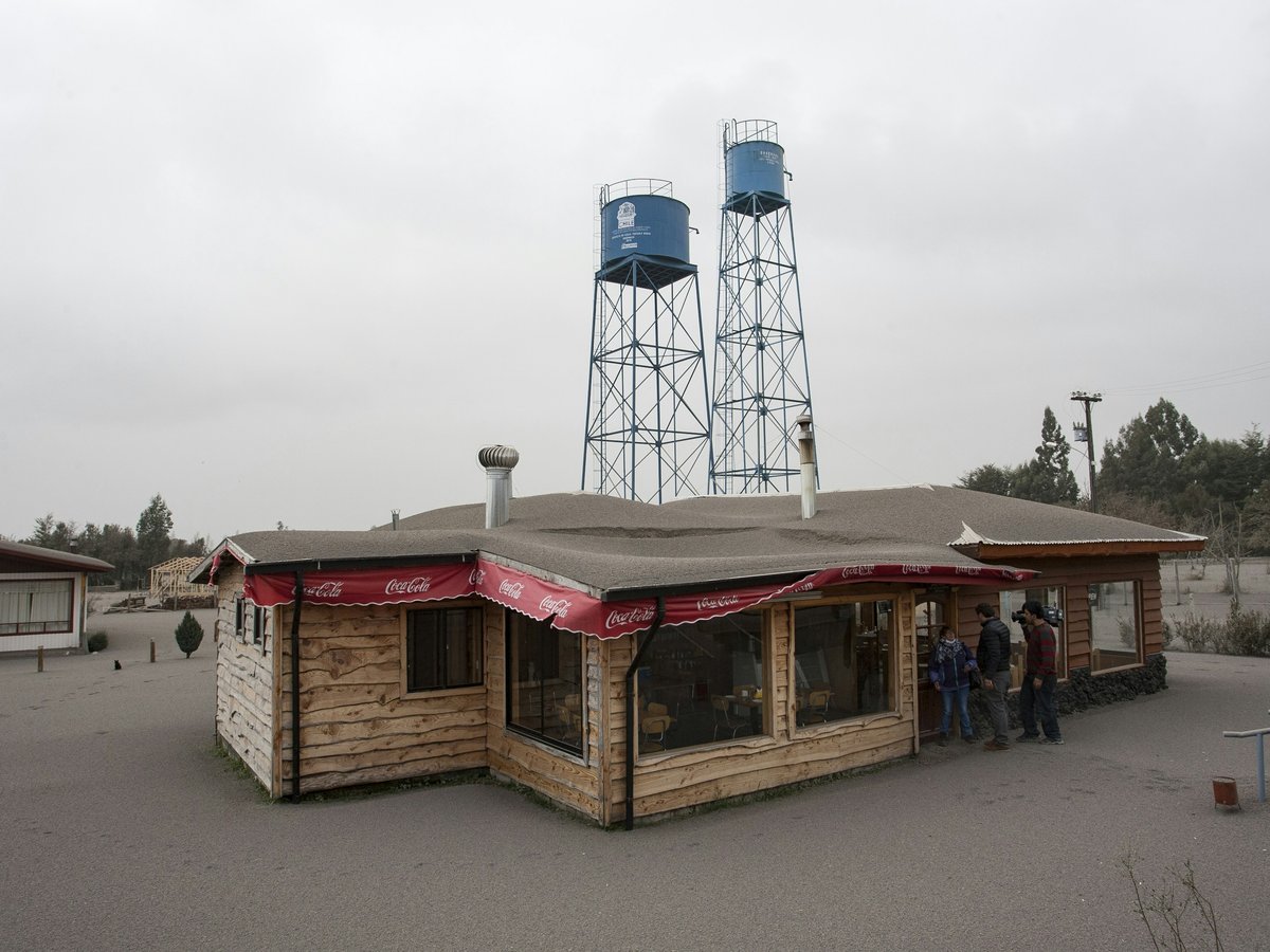 People near a wooden building and two tall water towers
