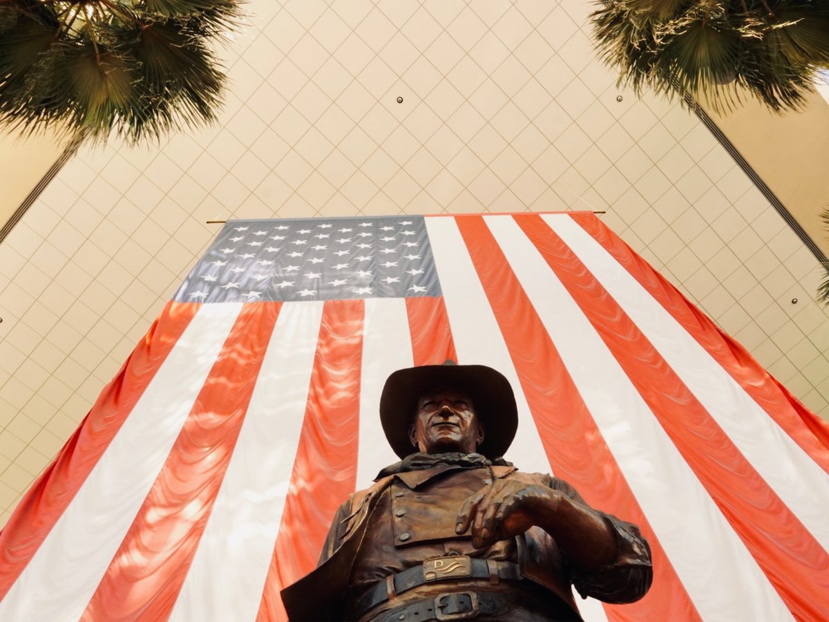 a statue of a man holding a gun in front of an american flag