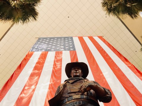 a statue of a man holding a gun in front of an american flag