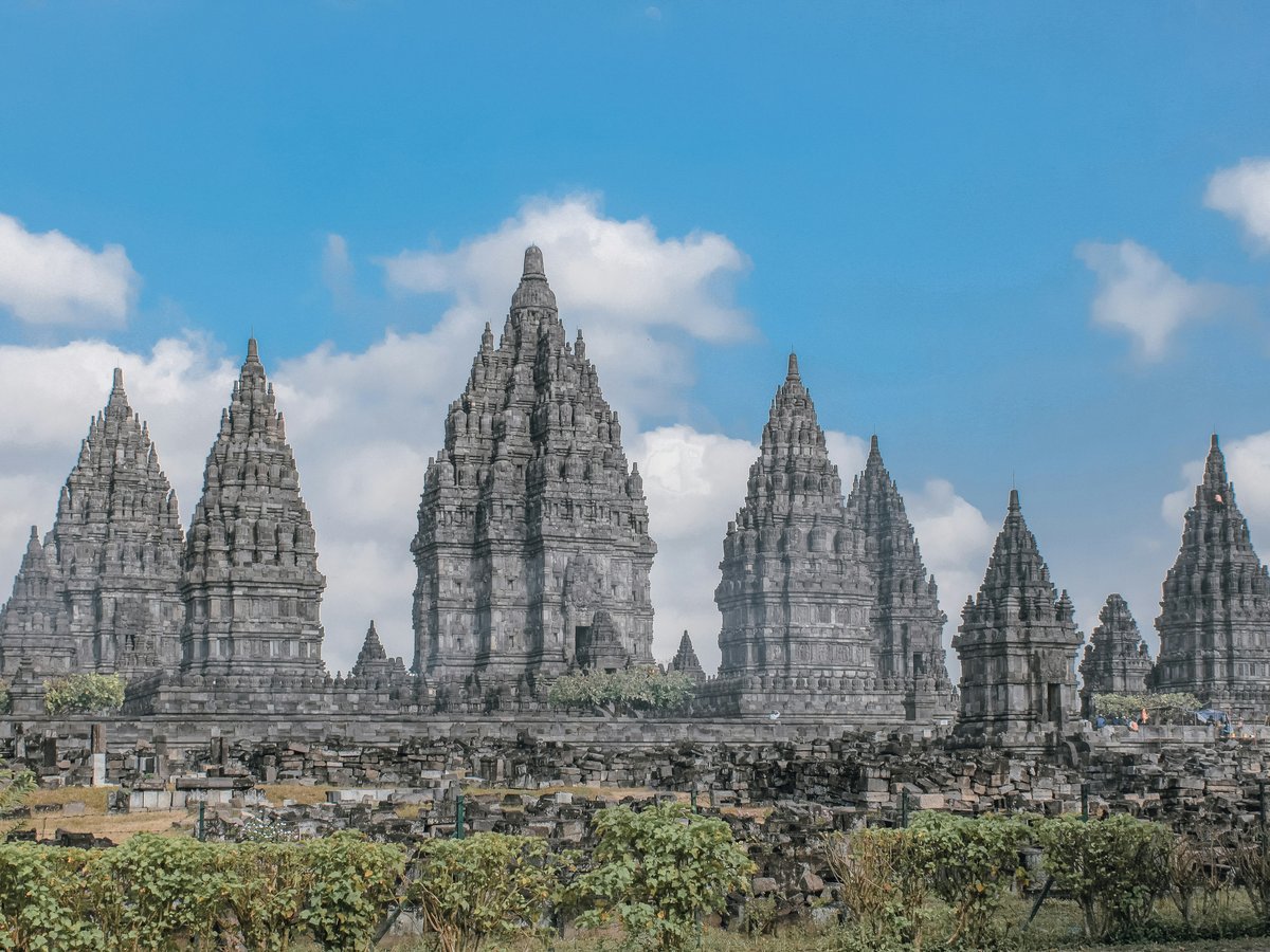 The stone spires of Prambanan temple complex under a bright blue sky