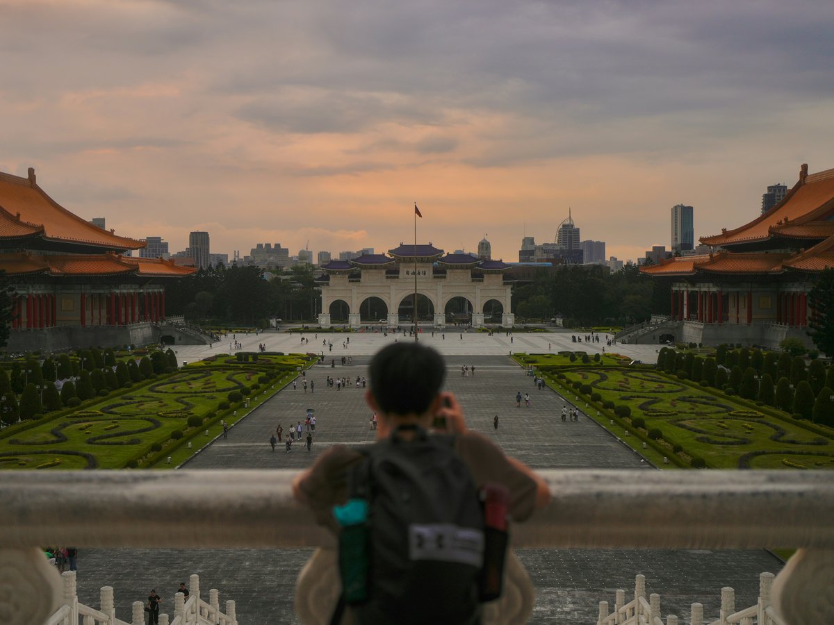 Person looking at a grand plaza with traditional buildings.