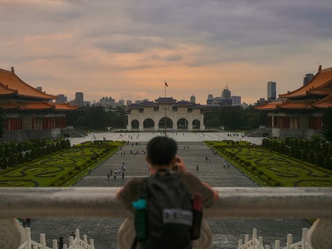 Person looking at a grand plaza with traditional buildings.