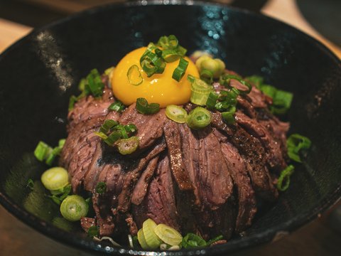 a black bowl filled with meat and vegetables