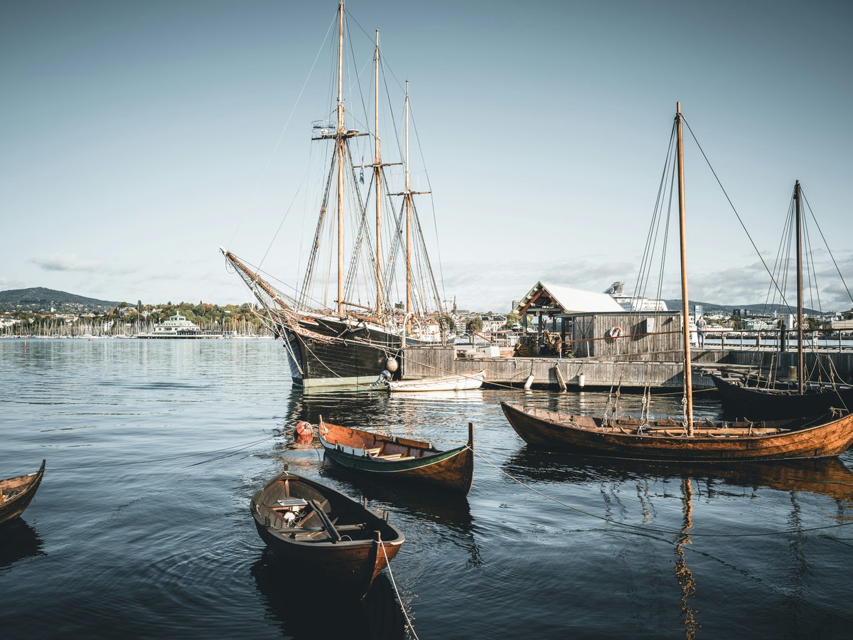 Boats and a tall ship float in tranquil waters.