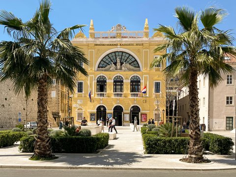 a yellow building with palm trees in front of it