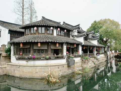 Traditional chinese architecture sits along a waterway.