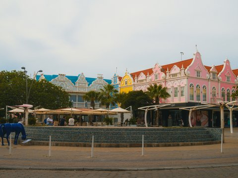 Colorful buildings line a waterfront promenade with people dining