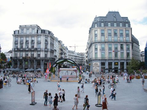A crowd of people walking around a city square