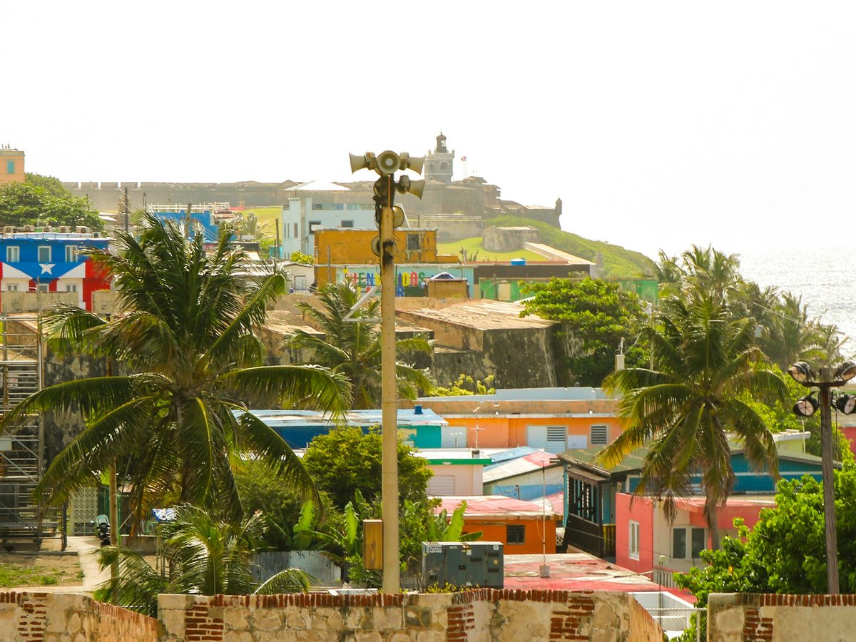 Colorful houses, palm trees, and a fort overlooking the ocean