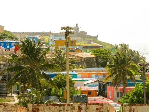 Colorful houses, palm trees, and a fort overlooking the ocean