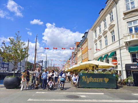 a group of people walking down a street next to tall buildings
